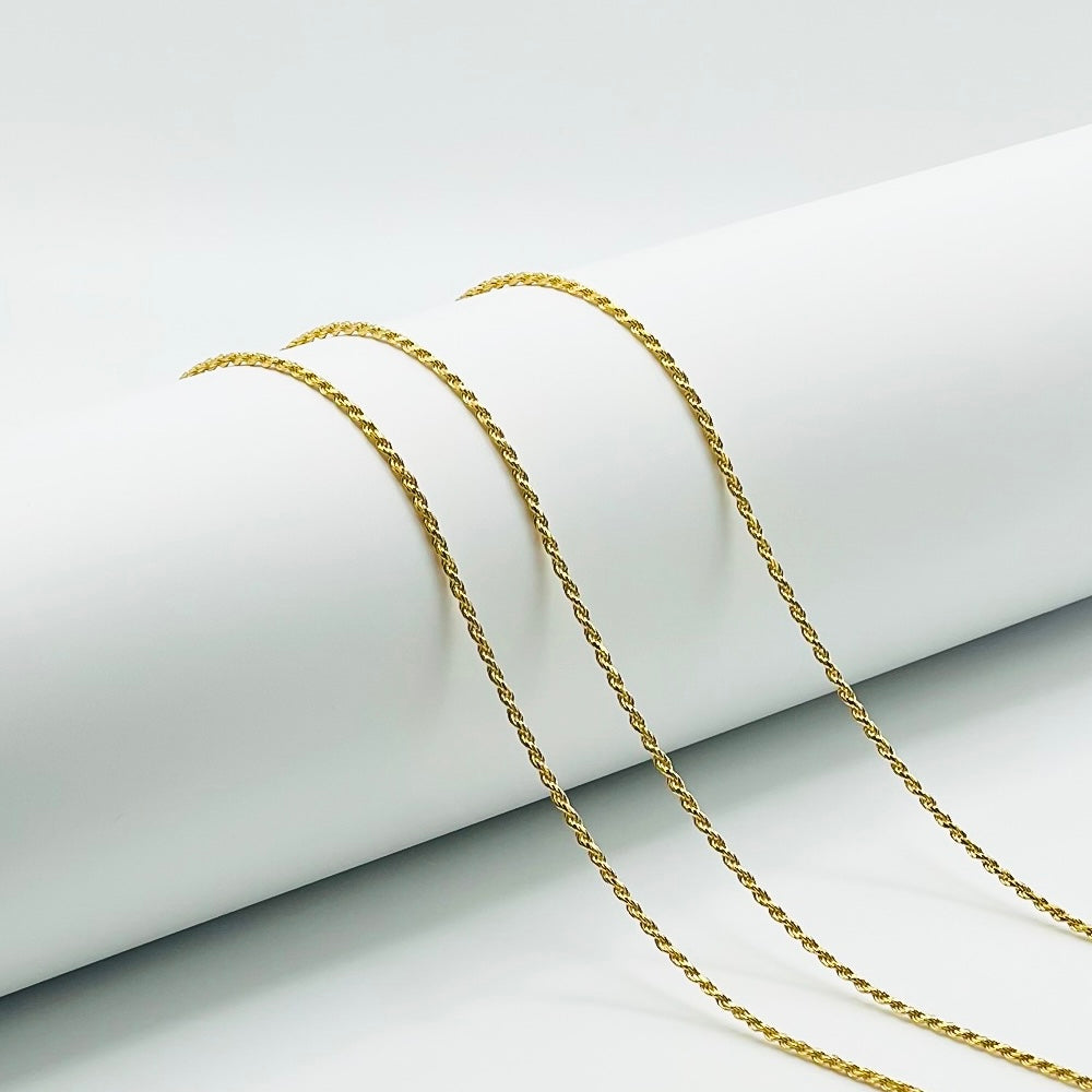 three gold rope chains are draped over a white cylinder with a white background