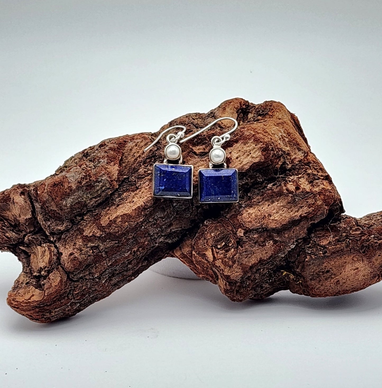 a pair of lapis earrings placed on a rustic piece of wood