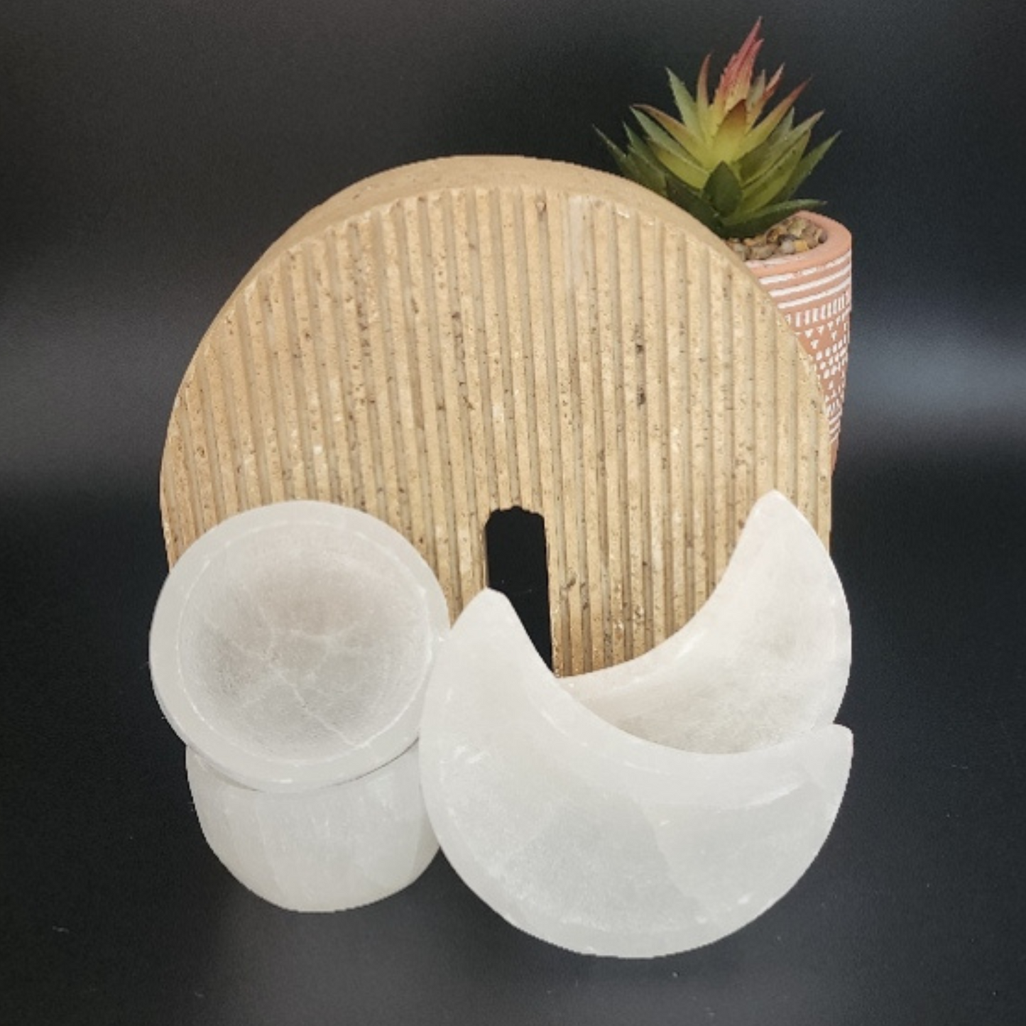 two small round selenite trinket bowls next to two crescent moon shaped trinket bowls set in a Bloom and Glow moody aesthetic.