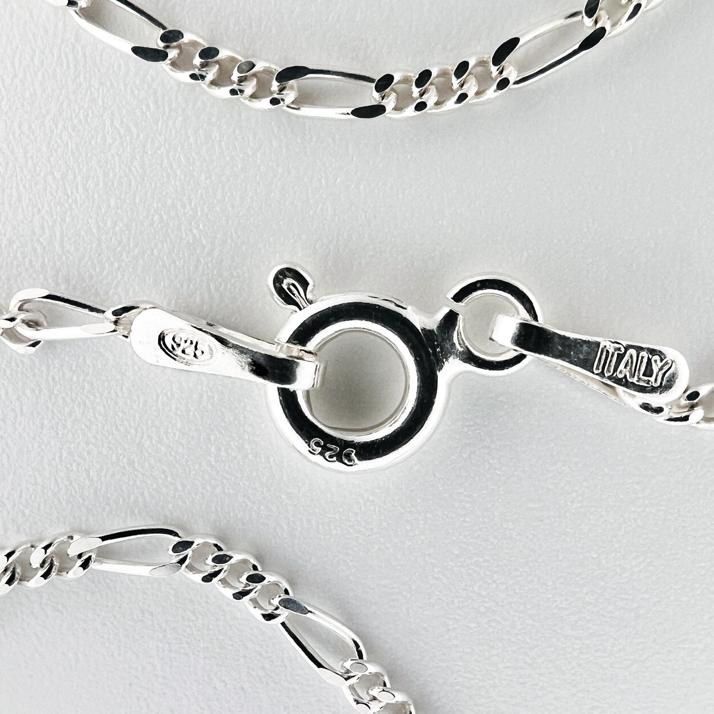 close up of closure with 925 silver stamp and clear pattern of figaro style chain is visible