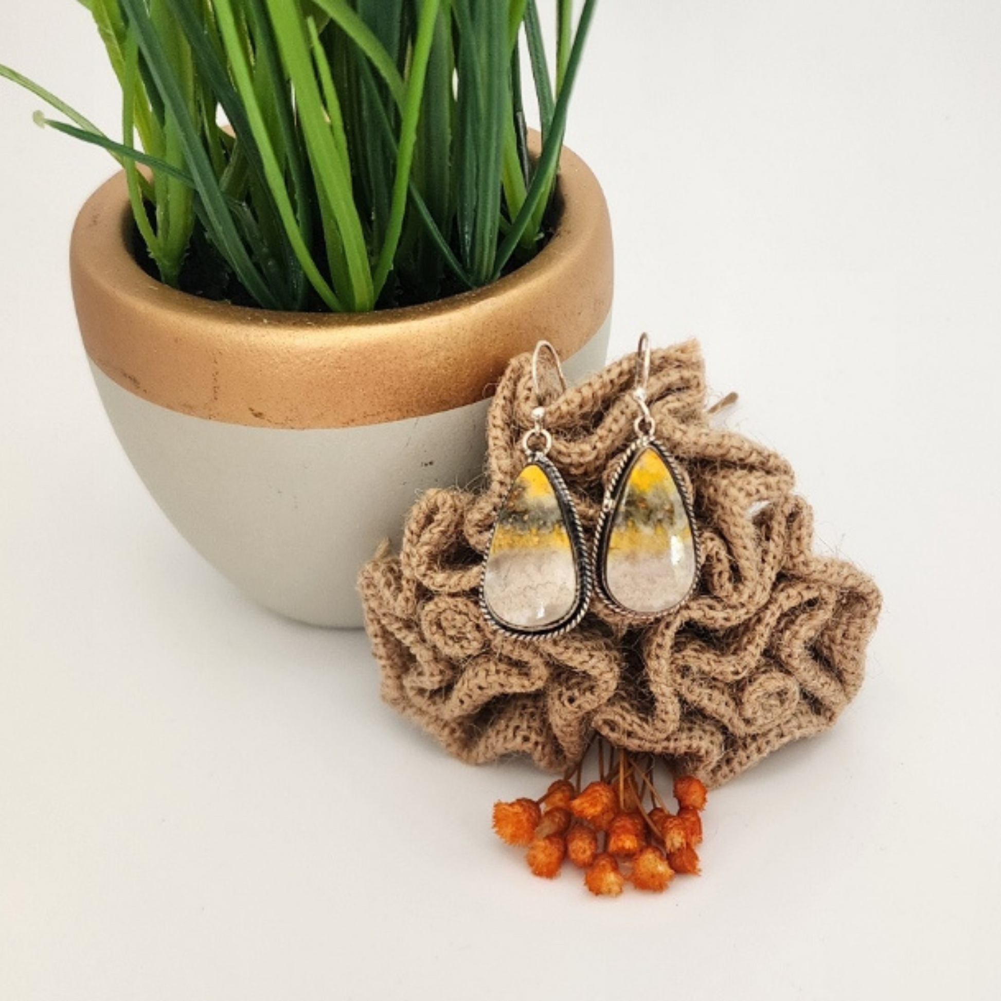 Pair of silver teardrop Bumblebee jasper  earrings on burlap with a potted plant in the background