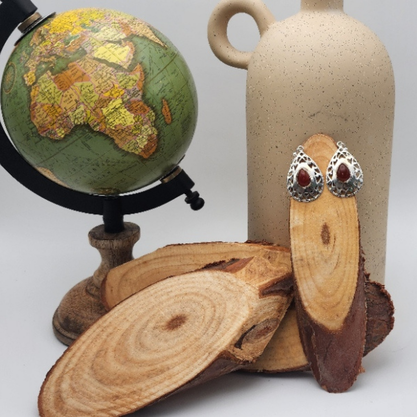 single pair of carnelian earrings displayed on a slice of wood staged and arranged in a moody Bloom and Glow aesthetic.