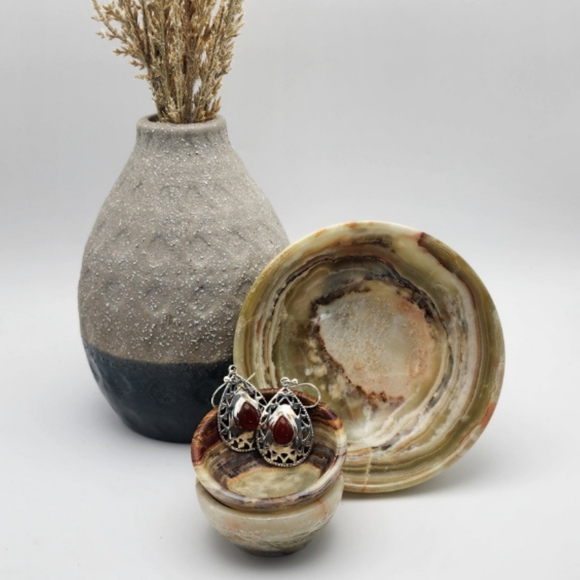 single pair of carnelian earrings displayed in a small onyx bowl that is placed inside another small onyx bowl staged and arranged in a moody Bloom and Glow aesthetic.