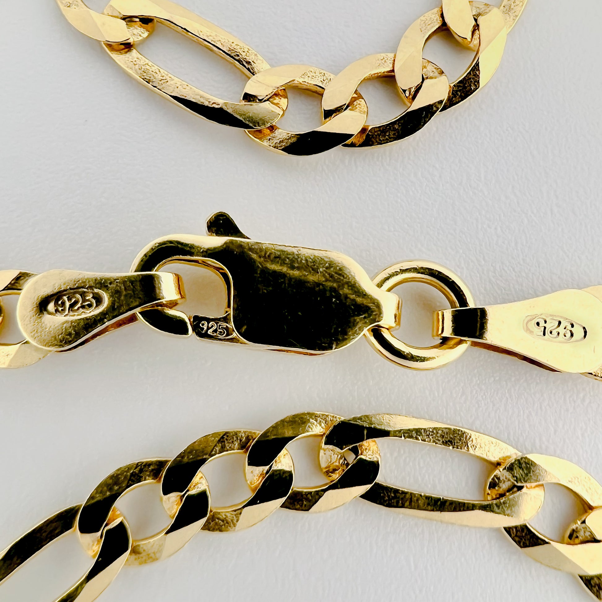 close up of clasp with 925 silver stamp and clear pattern of figaro style chain is visible
