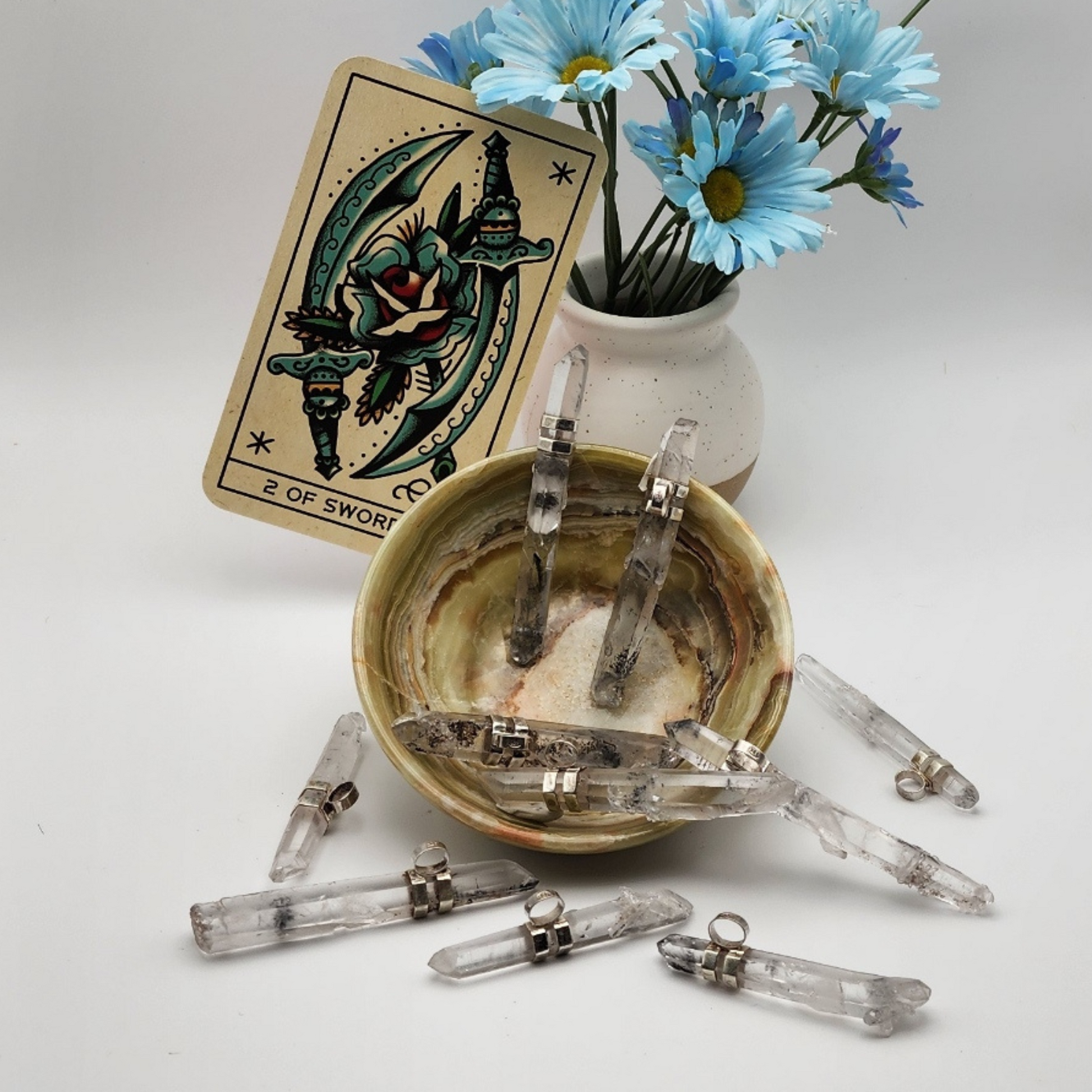 four lemurian pendants displayed inside of  an onyx trinket bowl with six additional pendants placed around the onyx bowl staged and arranged in a moody Bloom and Glow aesthetic scene.