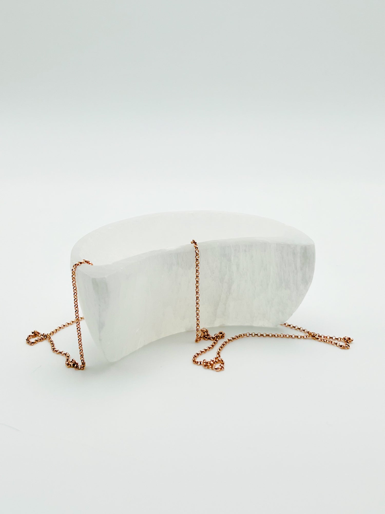 single crescent moon shaped selenite bowl set in a Bloom and Glow moody aesthetic. 