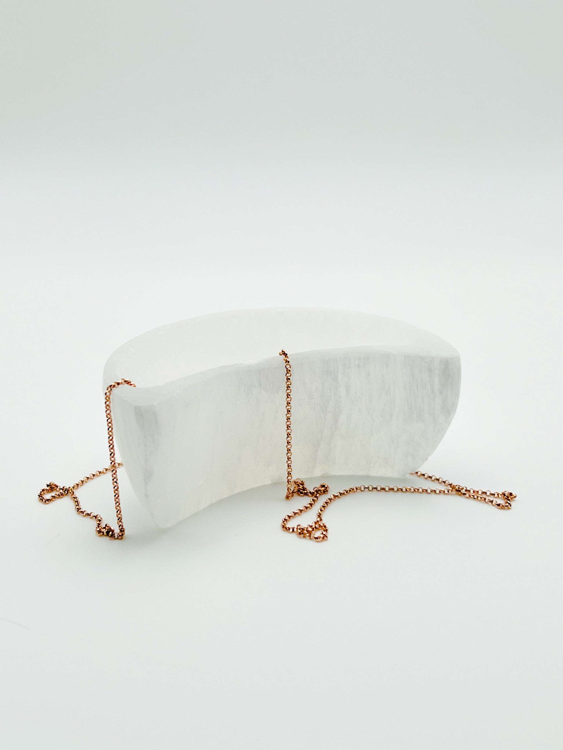 single crescent moon shaped selenite bowl set in a Bloom and Glow moody aesthetic. 