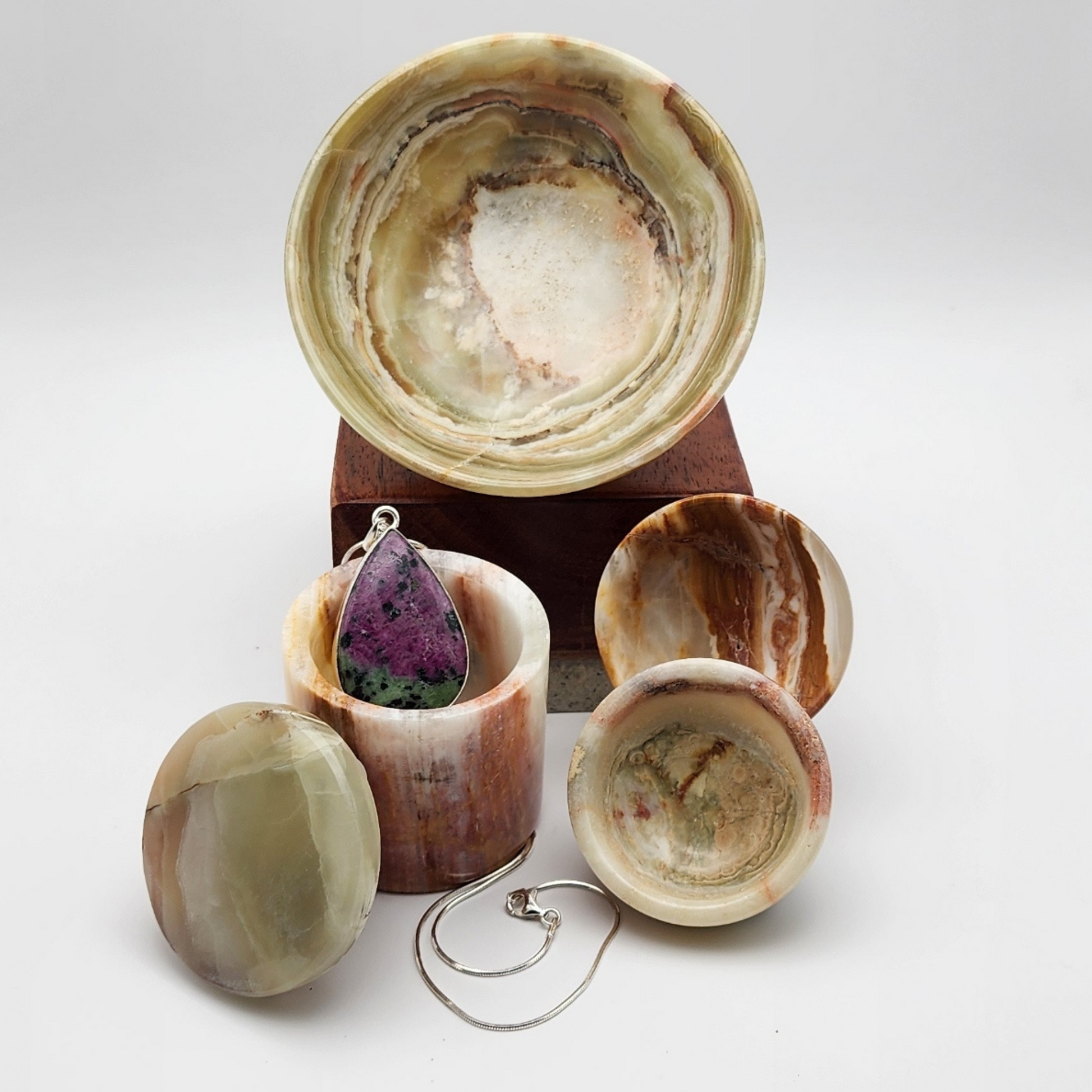 single ruby zoisite pendant displayed inside of a small onyx jewelry box with lid resting on the left side of the box staged and arranged in a moody Bloom and Glow aesthetic scene.