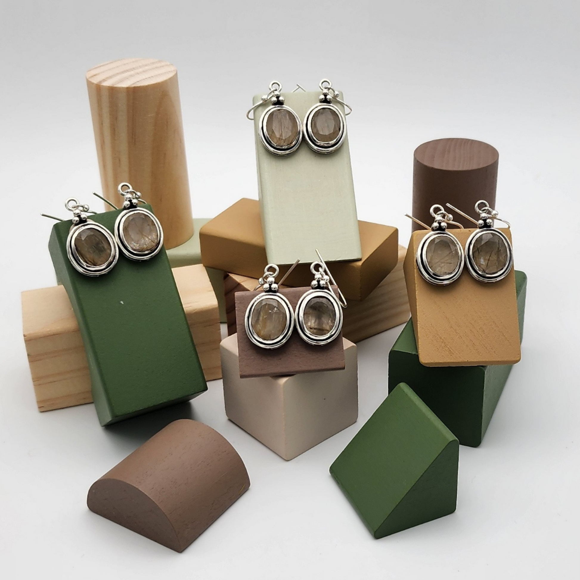 four pairs of faceted rutilated quartz earring staged on a set of multicolored blocks in various different shapes and sizes.