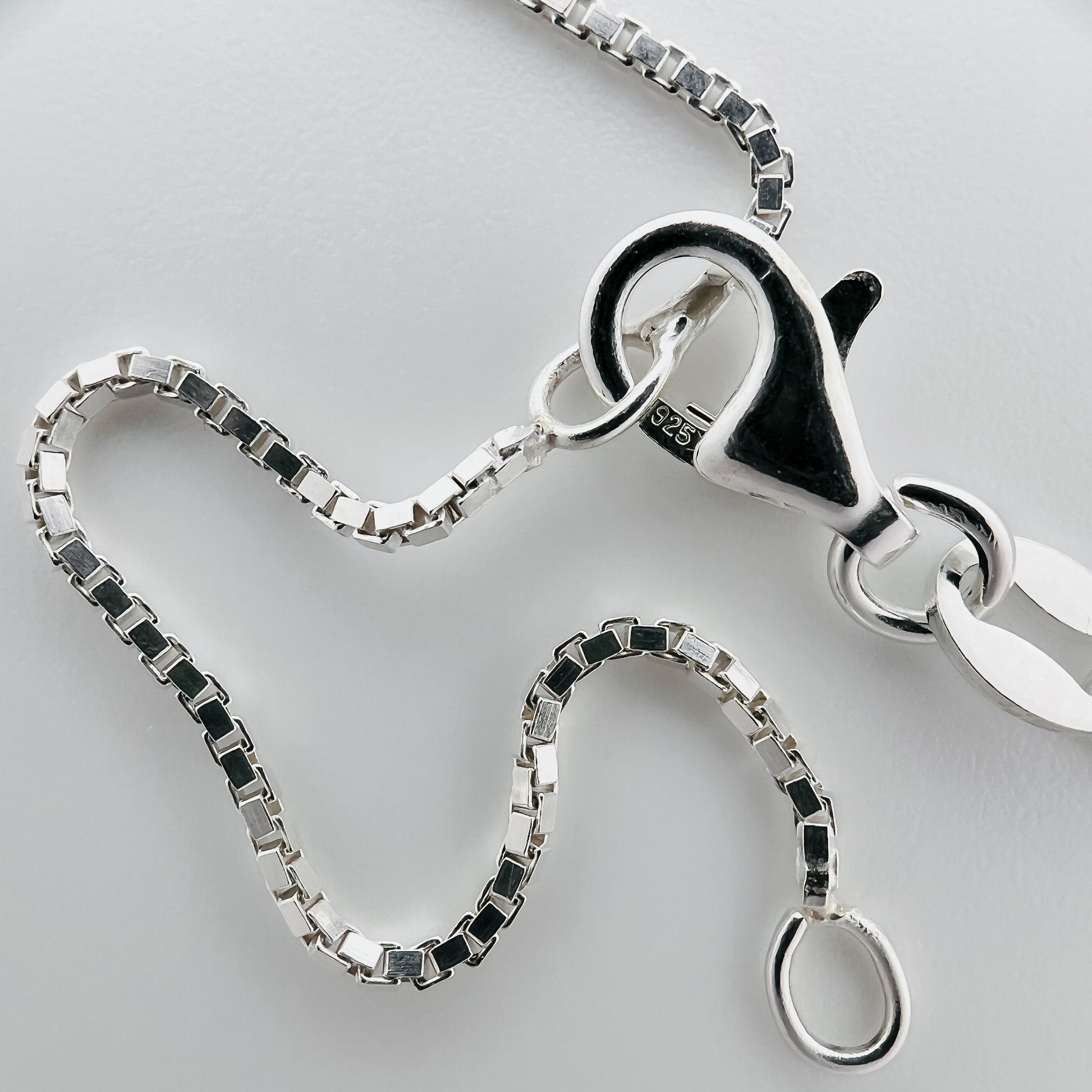 close up of closure with 925 silver stamp and clear pattern of box chain style chain and two adjustable closure points