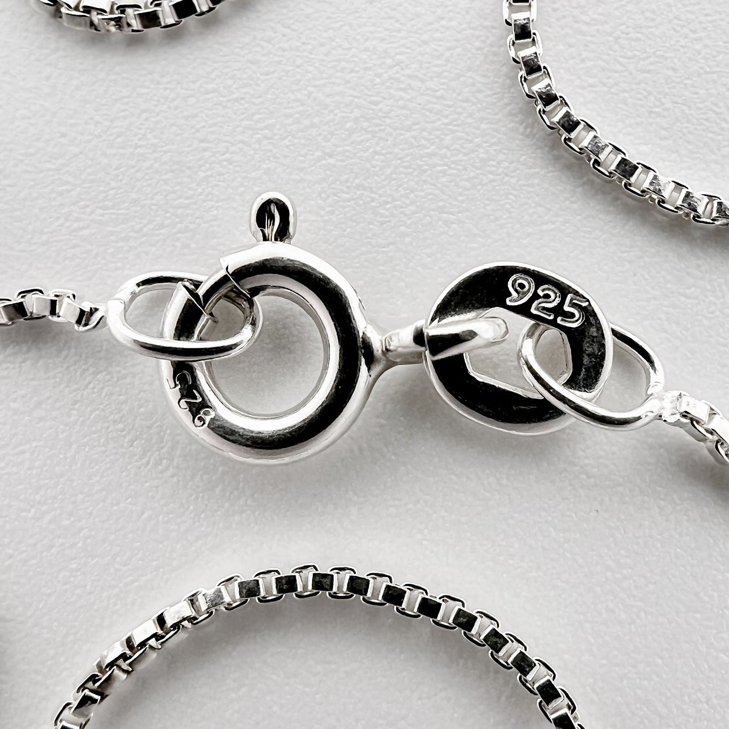 close up of clasp with 925 silver stamp and clear pattern of box style chain is visible