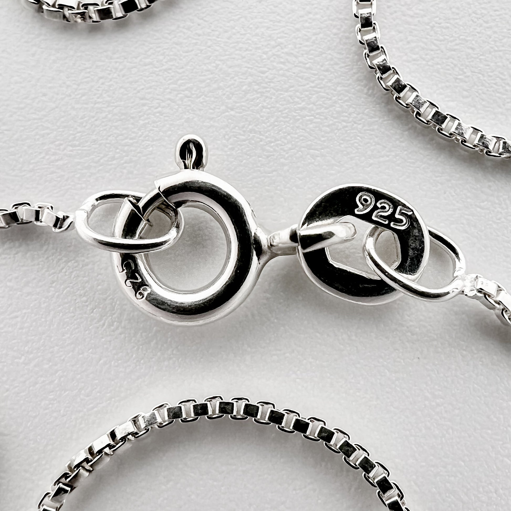 close up of clasp with 925 silver stamp and clear pattern of box style chain is visible