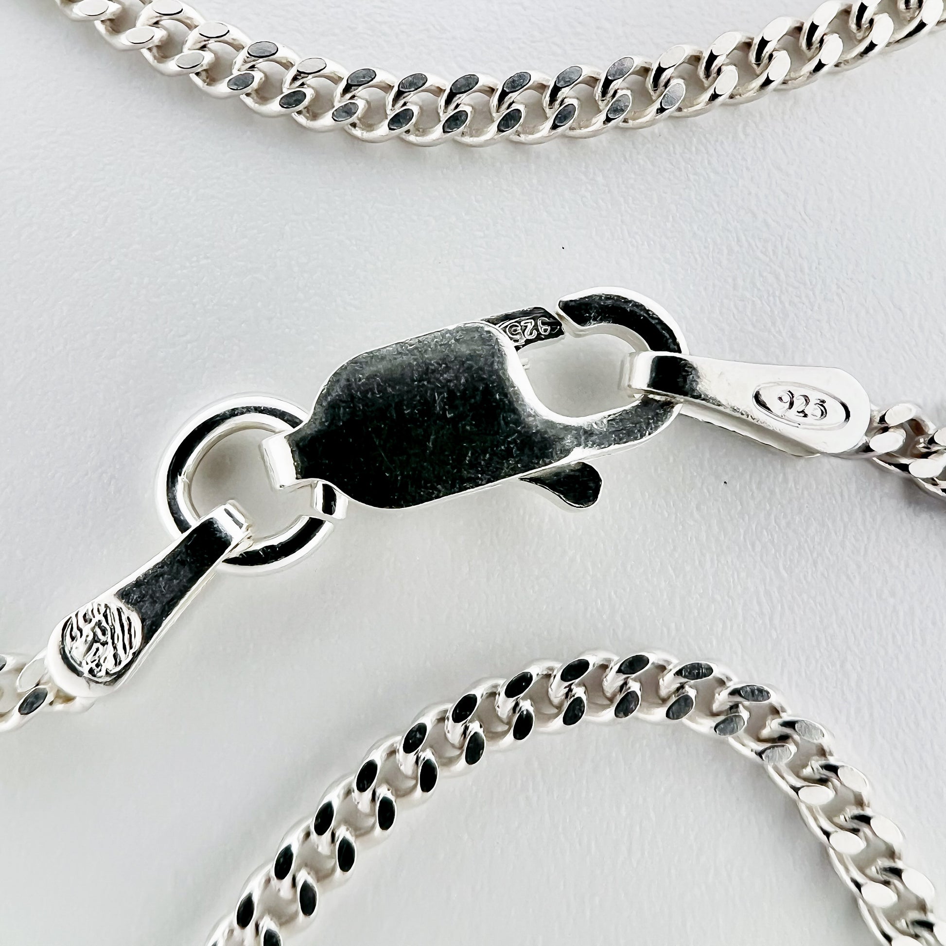 close up of clasp with 925 silver stamp and clear pattern of curb style chain is visible