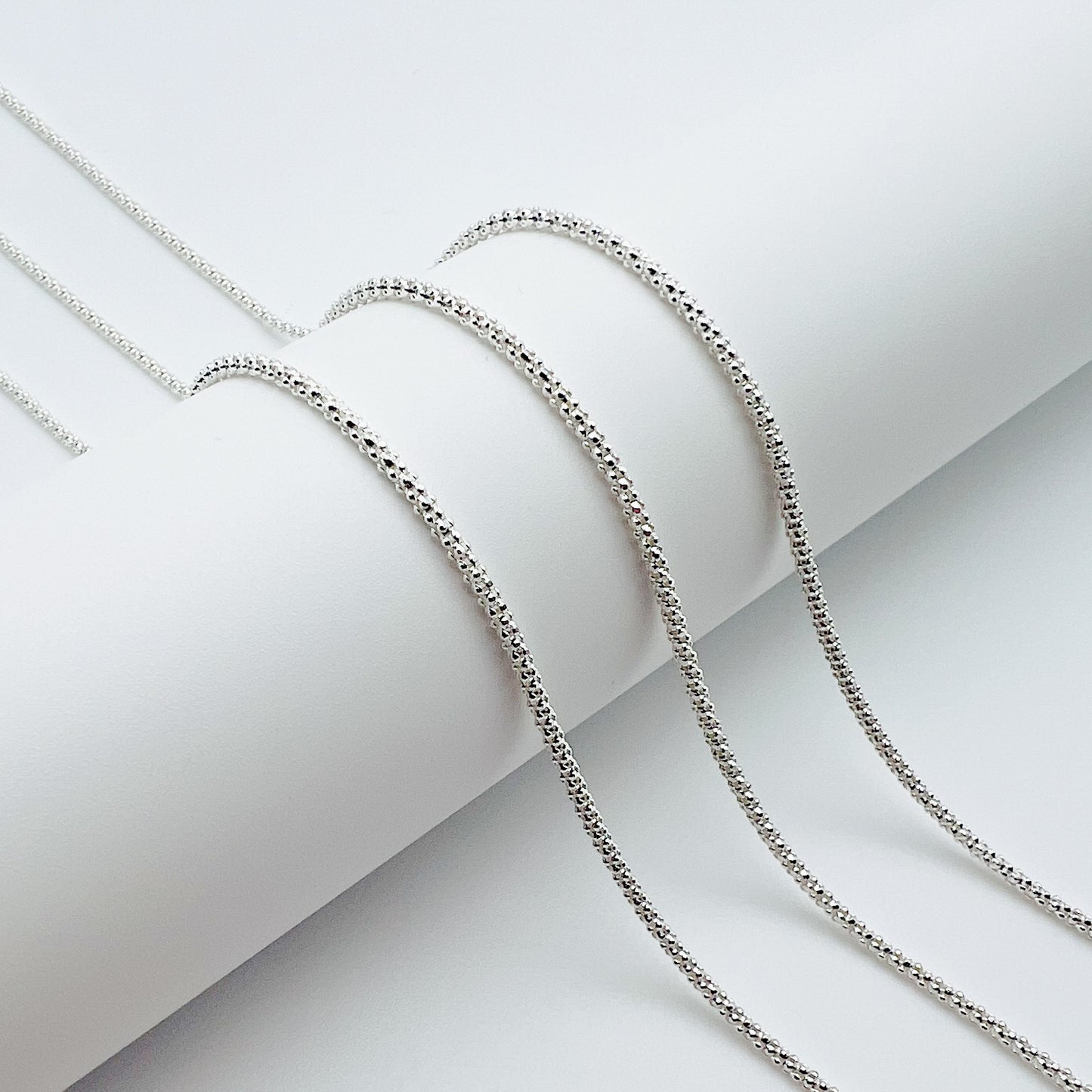 three popcorn chains draped over a white cylinder with a white background