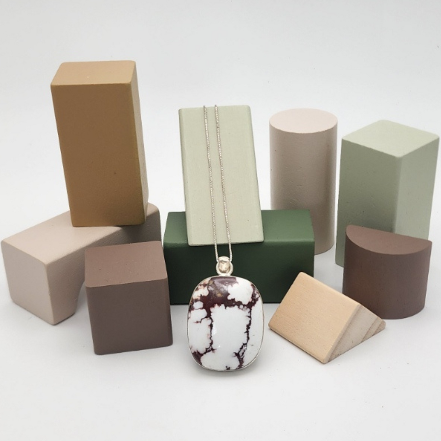 white buffalo turquoise pendant with a white background with colorful jewelry display blocks.